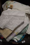 A box full of vintage and retro table linen including embroidered cloths.