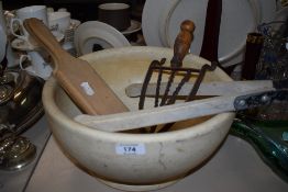 A Large heavy mixing bowl with spout, handled trivet,butter pats and a set of laundry tongs.