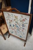 An early 20th century wood framed fire screen having embroidery to centre.