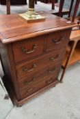 A modern hardwood chest of 2/3 drawers, of traditional design with brass bale handles.