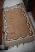 A vintage Aztec style rug, in beige and brown, some holes and fraying