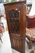 A mid to late 20th century oak linen fold corner cupboard, in the Priory style