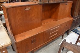 A vintage teak G plan or similar sideboard/cocktail cabinet with drop flap and slide door to top,