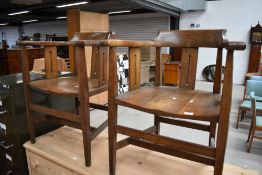A pair of Arts and Crafts oak elbow chairs , some splitting to one seat, usual wear but frames