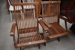 A pair of traditional teak folding garden chairs