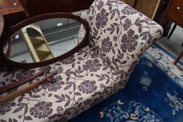 A modern chaise longue, upholstered in purple foliate patterned material.