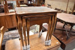 A reproduction nest of three tables having shaped tops with glass inserts