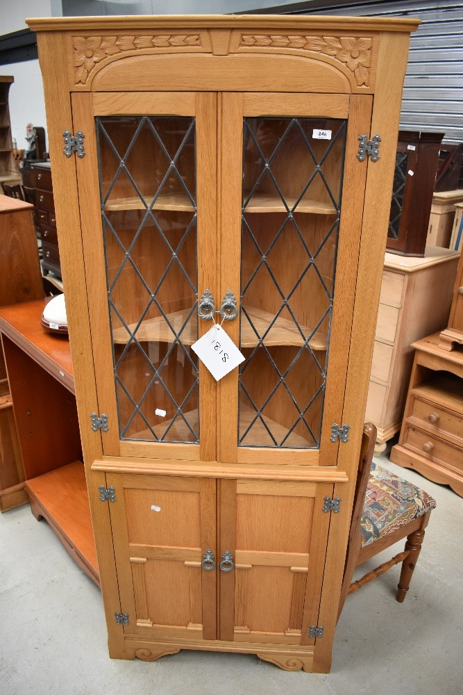 A Ferdinando reproduction golden oak style corner display having leaded glass doors to top and