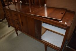 A vintage sapele sideboard having shelved section behind sliding ply doors and four drawers