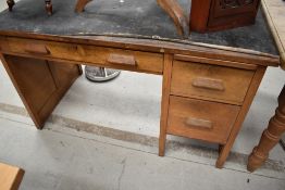 A 1950's oak desk, with long frieze drawer opposed by a bank of three drawers, crudely applied