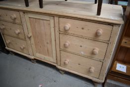 A Victorian stripped pine sideboard having central cupboard flanked by triple drawers having natural