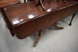 A Victorian drop leaf mahogany table having fluted centre support and brass lions paw feet on