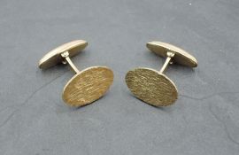 A pair of 9ct gold cufflinks having oval textured panels with bar connectors, approx 7.1g