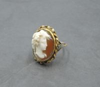 A conch shell cameo ring depicting a bacchanalian maiden in profile in a collared mount on a