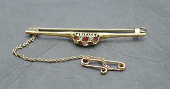A yellow metal, diamond and red stone bar brooch, with central domed platform with linear