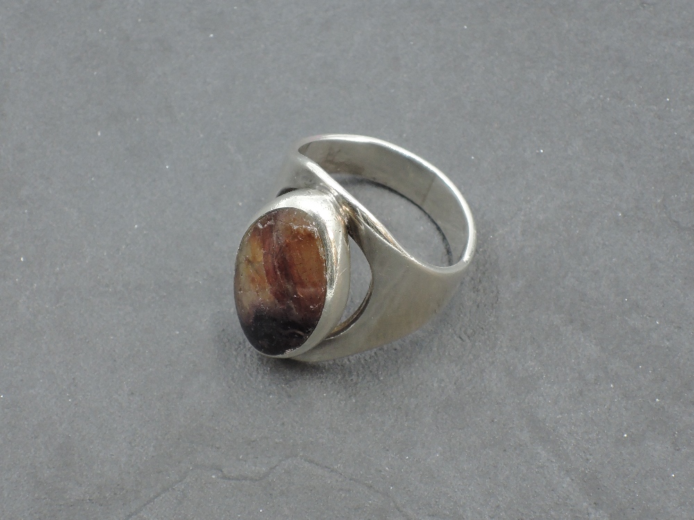 A large silver Artisan style silver ring having a Blue John panel in collared mount to open loop,