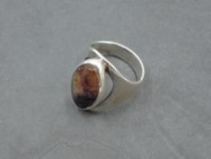 A large silver Artisan style silver ring having a Blue John panel in collared mount to open loop,