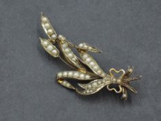 A yellow metal brooch in the form of a tied sprig having seed pearl decoration, bearing marks,