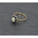 An oval Opal dress ring having sapphire and diamond chip surround on a 9ct gold loop, size O &