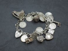 A white metal charm bracelet with padlock clasp stamped silver having 10 three penny coins and eight