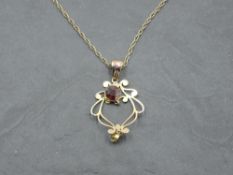 An Edwardian yellow metal pendant marked 9ct having garnet and peridot decoration on a yellow