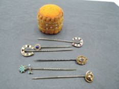 A collection of six yellow metal and 9ct gold stick pins of various forms including lucky horse shoe