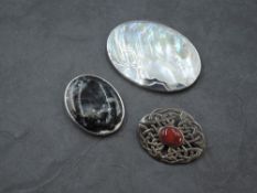 Three silver brooches including Celtic knot, stylised shell and moss agate