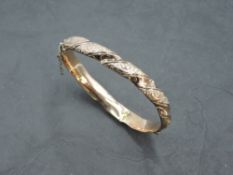 An Edwardian 9ct rose gold hinged bangle having moulded decoration, (AF), approx 9.2g