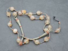 A late 19th/early 20th century strung agate bead necklace, with simple hoop and ball woven string