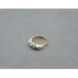 A Victorian ring having a trio of oval turquoise in a gallery mount on a yellow metal loop, marks