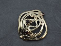 A yellow metal brooch/pendant of stylised form having garnet decoration, no marks but tests as 9ct