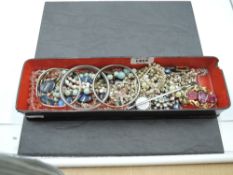 A lacquered glove box containing a selection of vintage and later costume jewellery including