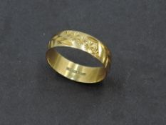 An 18ct gold wedding band having engraved floral and foliate decoration, size T/U & approx 3.1g