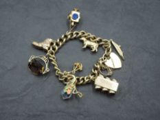 A 9ct gold charm bracelet with padlock clasp and eight 9ct gold charms including traffic lights,