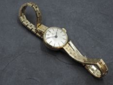 A lady's 9ct gold wrist watch by Tissot having baton numeral dial to champagne face in plain gold