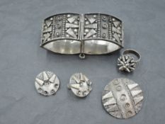 A suite of South American white metal jewellery, comprising hinged bracelet, brooch, earrings and