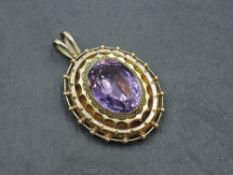 A Victorian/Edwardian amethyst pendant having a decorative moulded yellow metal surround stamped 10C