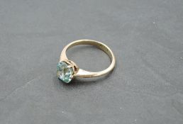 An aquamarine solitaire ring in a claw set mount on a yellow metal loop stamped 15ct, size N &
