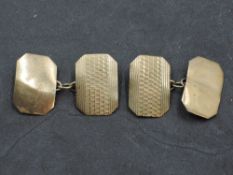 A pair of yellow metal cufflinks stamped 9ct of canted oblong form having engine turned decoration