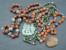 A Chinese string of carnelian beads interspersed by enamelled beads with jadeite carved pendant