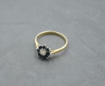 A sapphire and diamond chip cluster dress ring on a yellow metal loop stamped 18ct, size N/O & 2.4g