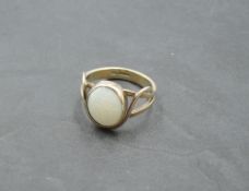An faux opal oval stone ring having a collared mount in twist and open shoulders on a 9ct gold loop,