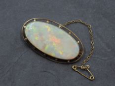 An opal brooch of oval form in a collared open mount stamped 9ct, GW approx 7.2g & 42mm long