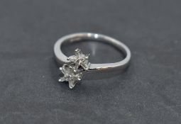 A diamond daisy double head dress ring having small baguette cut diamonds to cross over shoulders on
