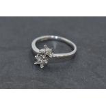 A diamond daisy double head dress ring having small baguette cut diamonds to cross over shoulders on