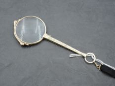 An early 20th century yellow metal lorgnette, of traditional design with scroll engraved tapering