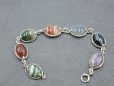 A seven panel mixed agate bracelet in white metal collared mounts stamped silver with chain