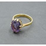 An Oriental oval amethyst dress ring in a raised claw mount on a 14ct gold loop bearing possibly