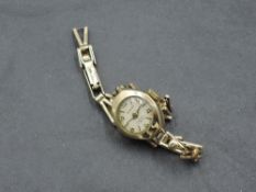 A lady's 9ct gold wrist watch having Arabic and baton numeral dial to small circular face in 9ct