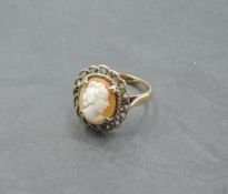 A cameo ring depicting a maiden in profile in a decorative mount on a yellow metal loop stamped 9ct,